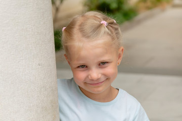 Closeup portrait of a cute smiling young girl near a white wall in the city