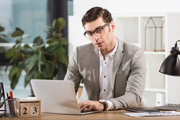 handsome stylish businessman working with laptop at office