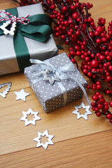 Christmas silver gift boxes on wooden table with red berries decoration. Christmas festive background