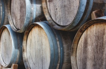 Wooden barrels stacked in a pile with vintage wine at a vineyard