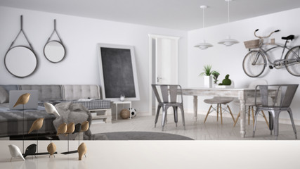 White table top or shelf with minimalistic bird ornament, birdie knick - knack over blurred modern living room with pallet sofa and vintage dining table, modern interior design
