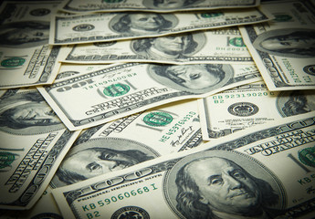 One hundred dollars pile as background.