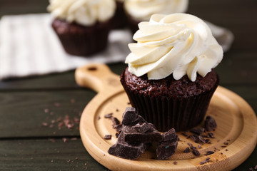 Tasty chocolate cupcake on wooden board