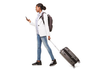 Full body portrait of young black woman walking with suitcase and mobile phone