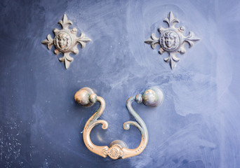 Exterior vintage door handle with a bronze finish on a front door of an ancient building in Catania, Sicily, Italy