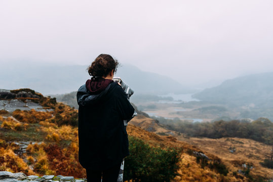 Young woman takes a picture in misty landscape in Ireland