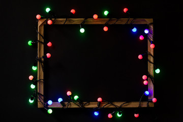 Christmas lights in a frame on black background. Holiday, New Year season, minimal concept.
