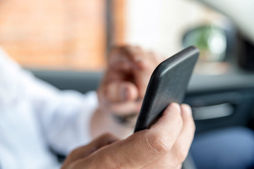 Businessman working on tablet and smartphone inside car on bright day