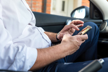 Businessman working on tablet and smartphone inside car on bright day