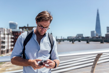 UK, London, man using his smartphone on the Millennium Bridge