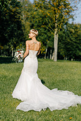 fashionable bride with short hair with a big bouquet posing in the park