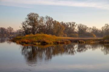 jesienny brzeg rzeki o wschodzie słońca z mgłą