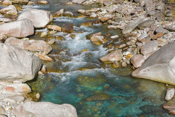 Fiume che scorre tra i sassi grigi in estate
