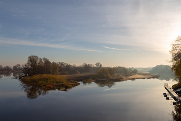 Fototapeta na wymiar jesienny brzeg rzeki o wschodzie słońca z mgłą