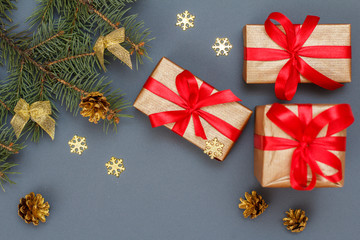 Gift boxes, fir tree branches with cones on gray background