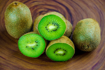 Sliced fresh and juicy kiwi fruit halves on a wooden background.