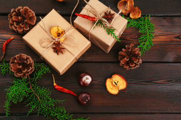Christmas composition. Christmas gift, knitted blanket, pine cones, fir branches on wooden background.