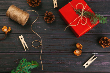 Christmas composition. Christmas gift, knitted blanket, pine cones, fir branches on wooden background.