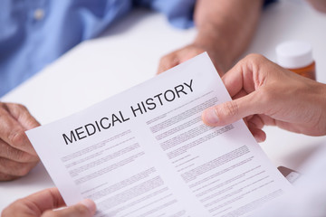 doctor reading the medical history of a senior man