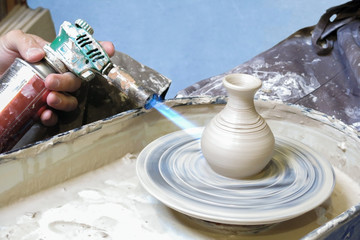 pottery creating and burning a clay pot with a gas burner on  pottery wheel