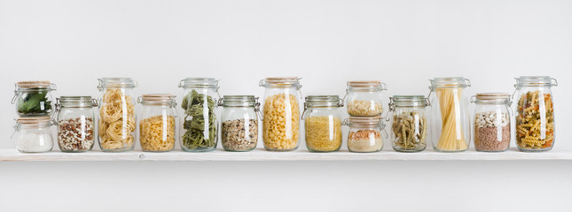Assortment of uncooked groceries in glass jars arranged on shelf