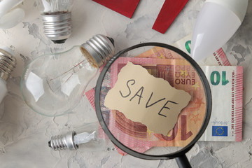 The concept of saving electricity. money and different bulbs close-up with the inscription save. Euro