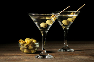 Martini in a glass wineglass with green olives on a skewer on a brown wooden table. cocktails. bar