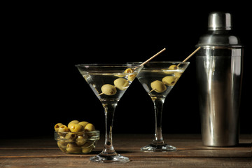 Martini in a glass wineglass with green olives on a skewer on a brown wooden table. cocktails. bar