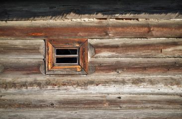 Small wood window in the wall of old wooden log house. Space for text.