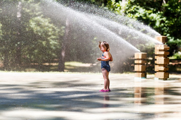 a girl having fun in the fountain on a hot summer day. family and love concept