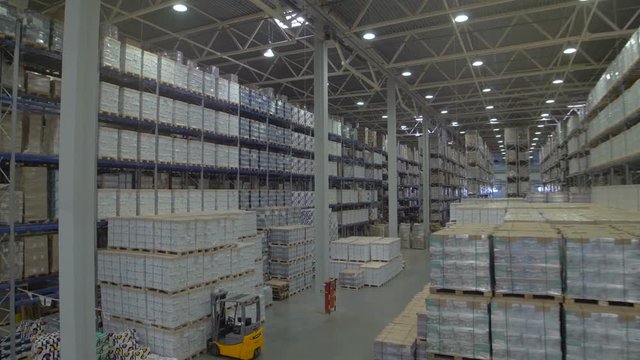 Huge warehouse and forklifts, racks with goods.