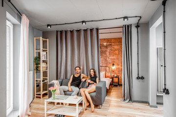 Modern living room with young lovely couple on the couch at their apartment