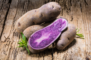 Vitolette noir or purple potato. On a wooden background.