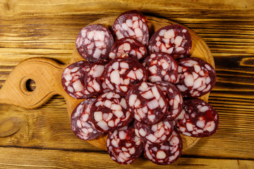 Sliced salami sausage on cutting board on wooden table. Top view