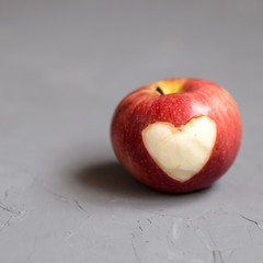 Apple with engraved heart, copy space, grey background