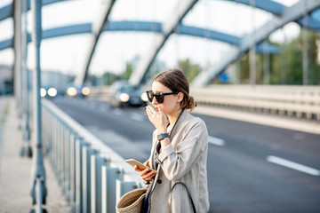 Woman closing her nose feeling bad because of the air pollution on the bridge with traffic in the...