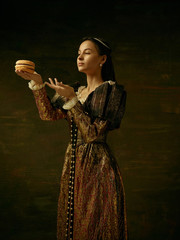 Girl in medieval beautiful dress or costume of the countess at dark studio.