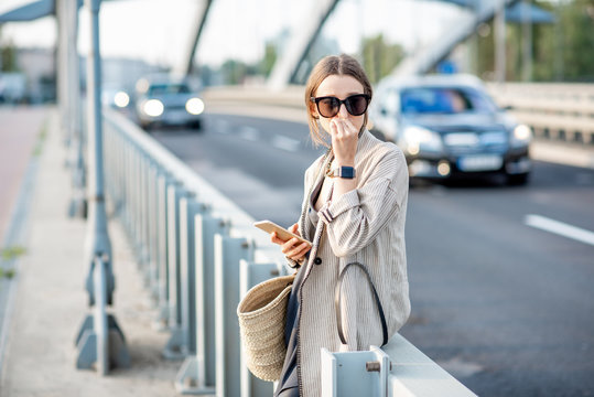 Woman Closing Her Nose Feeling Bad Because Of The Air Pollution On The Bridge With Traffic In The City