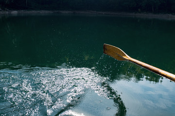 Oar of boat touching water and causing splash and ripples in the water A wooden paddle on a boat...