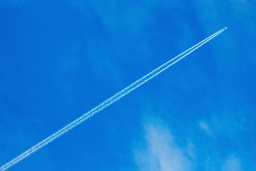 An airplane and a trail from an airplane in a blue sky_