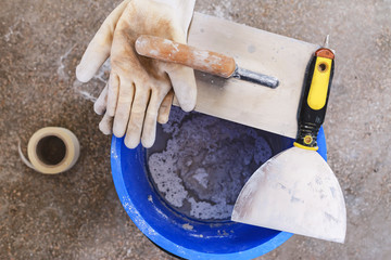 Bucket with plaster and metal building spatula for to put plaster filler on the wall