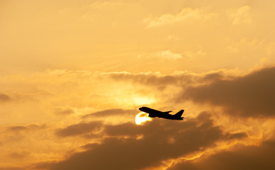Fototapeta na wymiar Silhouette of commercial airplane against beautiful orange sky at sunset