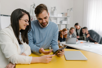 Obraz premium Two colleagues discussing product design with coworkers in background
