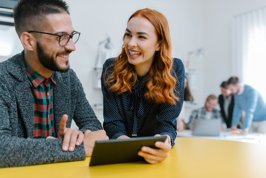 Redhead businesswoman smiling broadly with her colleague in the foregound