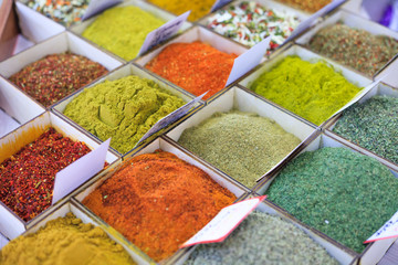 Close-up of different types of colored oriental spices and seasonings on market in square forms with price tags