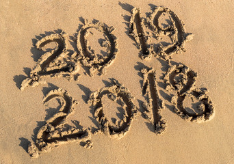 New year 2019 concept. Inscription 2018 and 2019 on a beach sand.
