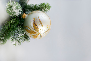 silver Christmas ball with a Golden pattern with a green spruce branch on a gray blue background