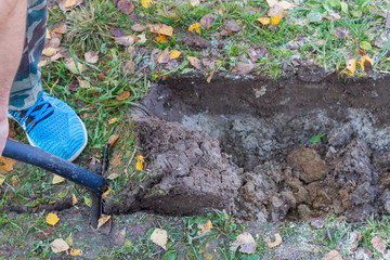 Fototapeta premium Man digging a ditch with a shovel in autumn