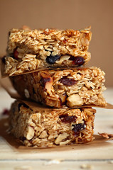 Homemade granola bars with nuts and cranberries over wooden background