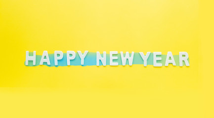 Sign and Symbol text of wooden Happy new Year  on bright yellow paper background.